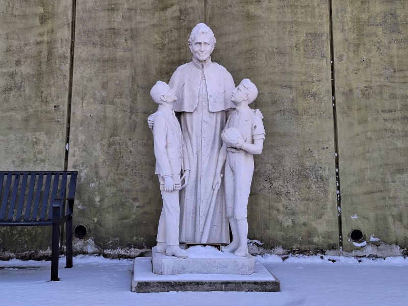 Statue of Don Bosco and boys in the snow in East Boston