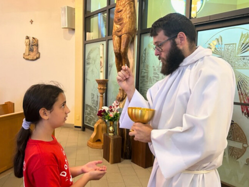 Br. John Castonguay, SDB, gives Holy Communion