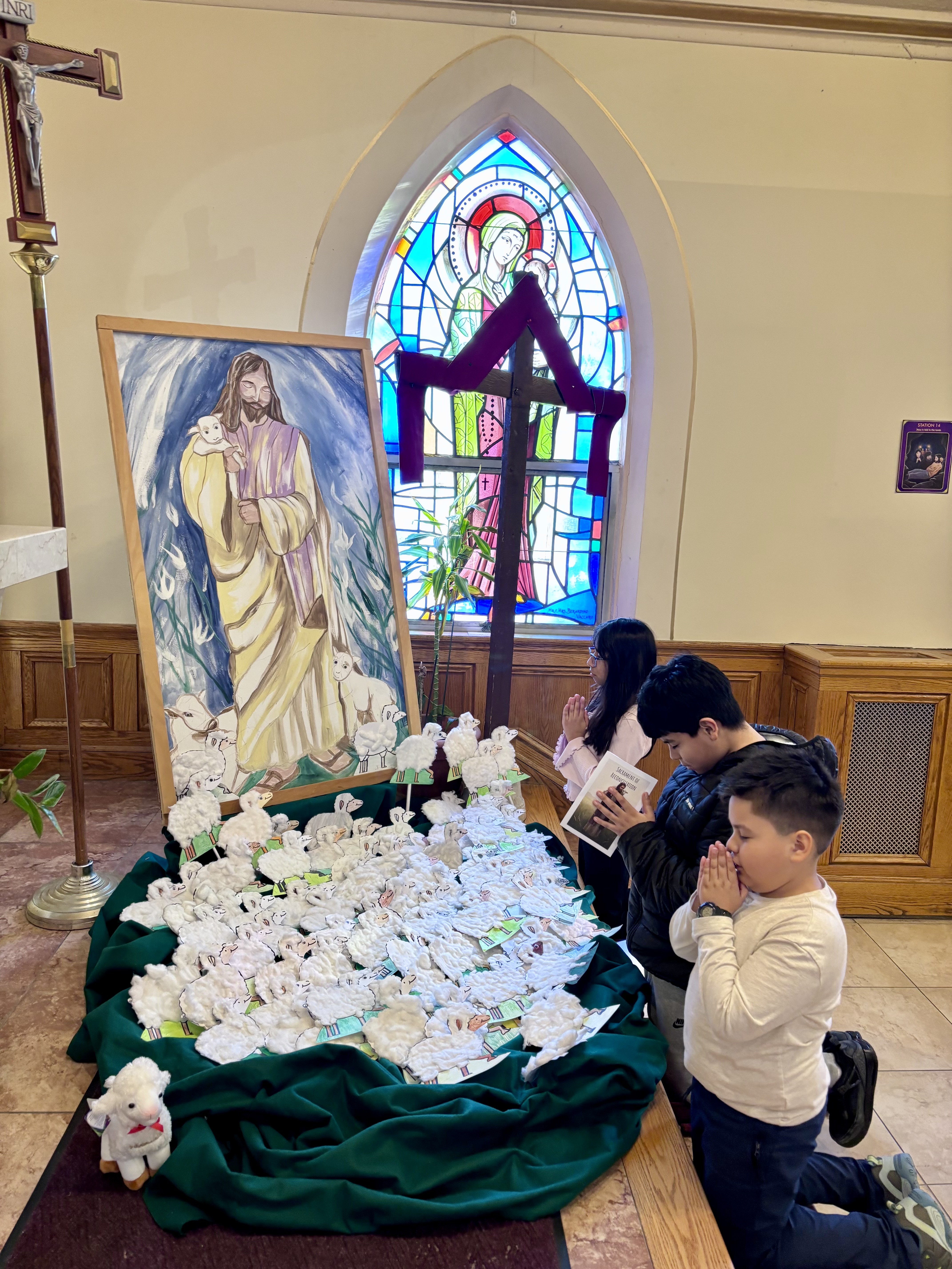 Port Chester: Children pray after they place the sheep they made to represent themselves being led by the Good Shepherd by a painting of Jesus as the Good Shepherd.