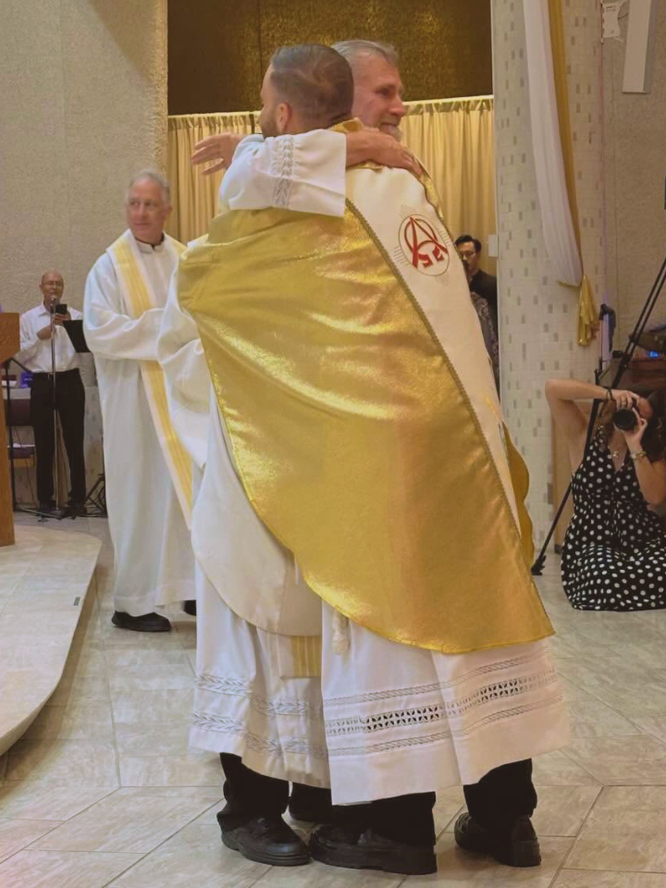 Fr. Dave Sajdak, SDB, embraces a newly ordained Fr. Tom.