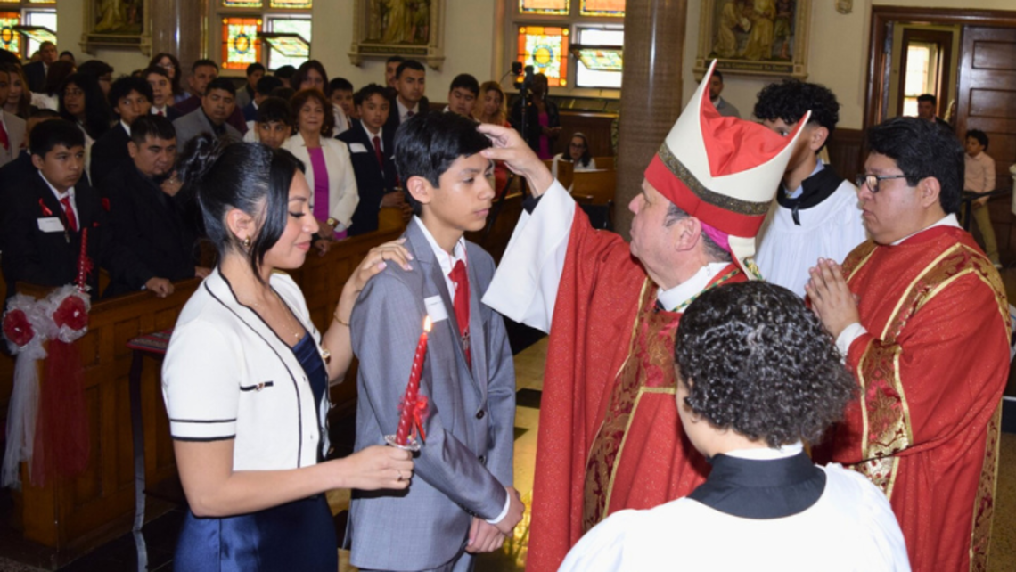 Most Reverend Bishop Manuel Cruz, DD, confirms a young man at St. John Bosco Parish. | Credit: Gloria Wang Port Chester: Confirmation